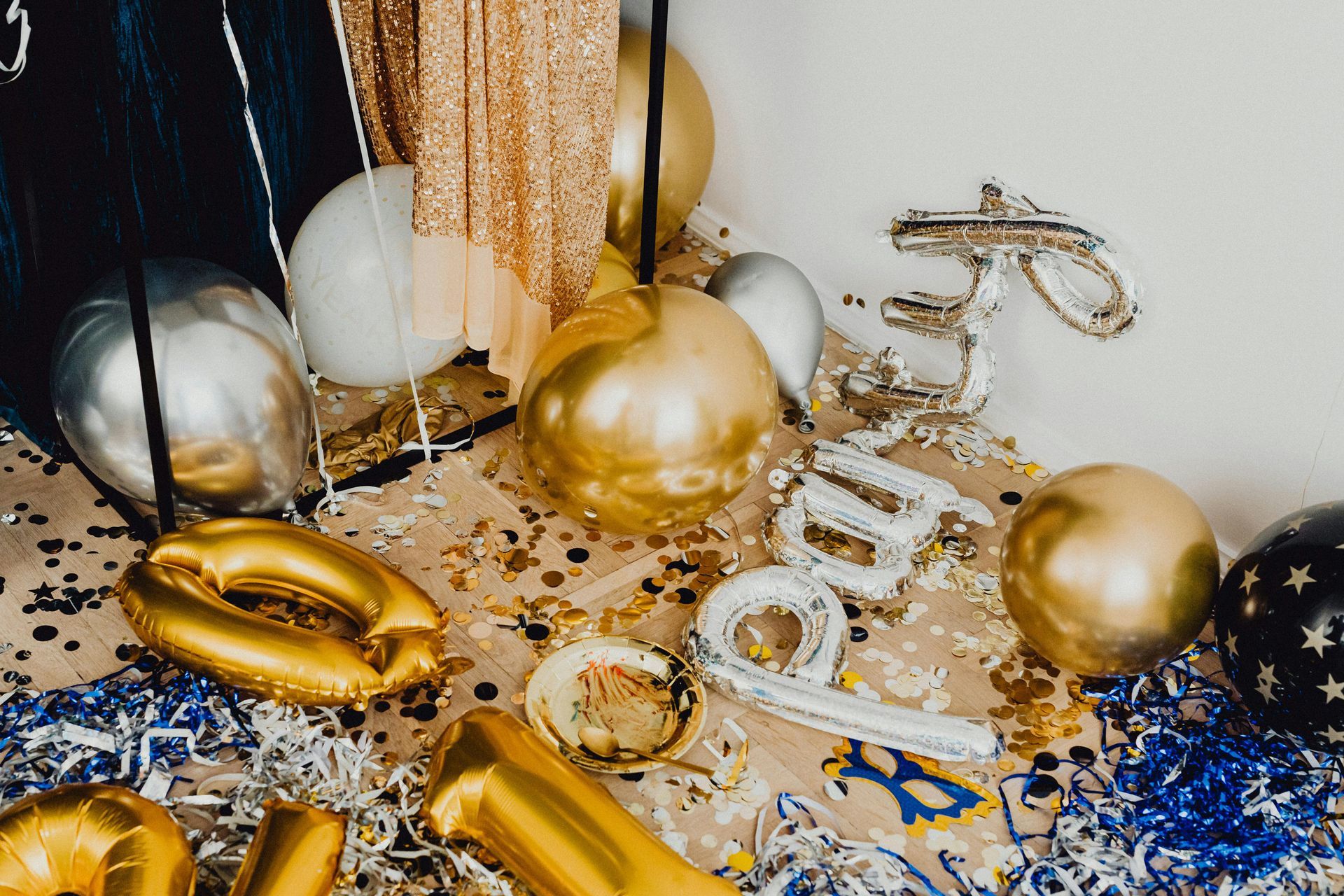 Gold and silver party balloons, confetti, and a white “2024” decoration on the floor.