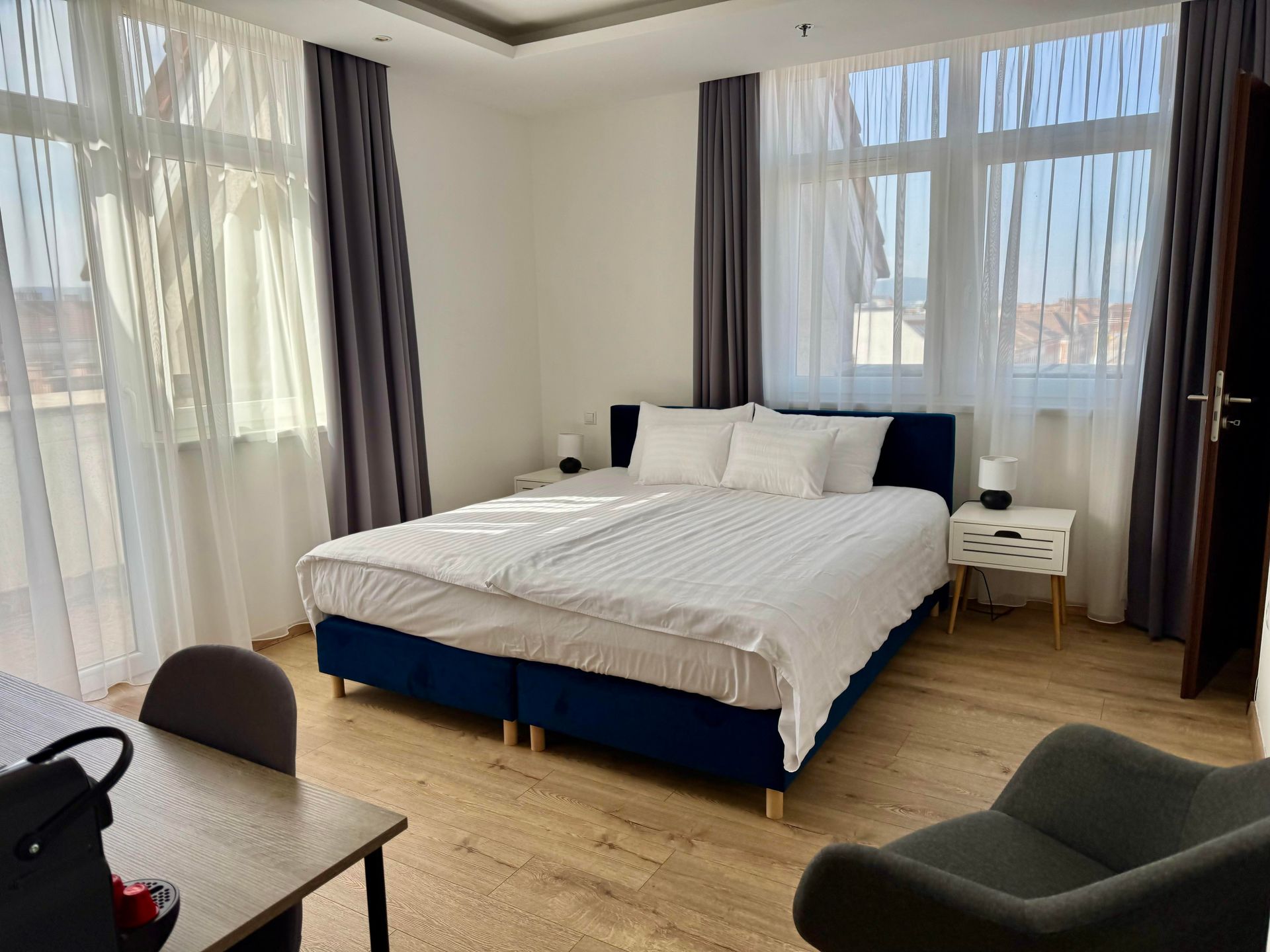 Bedroom with a double bed, two bedside tables, a desk, and a chair. Light-filled room with window.