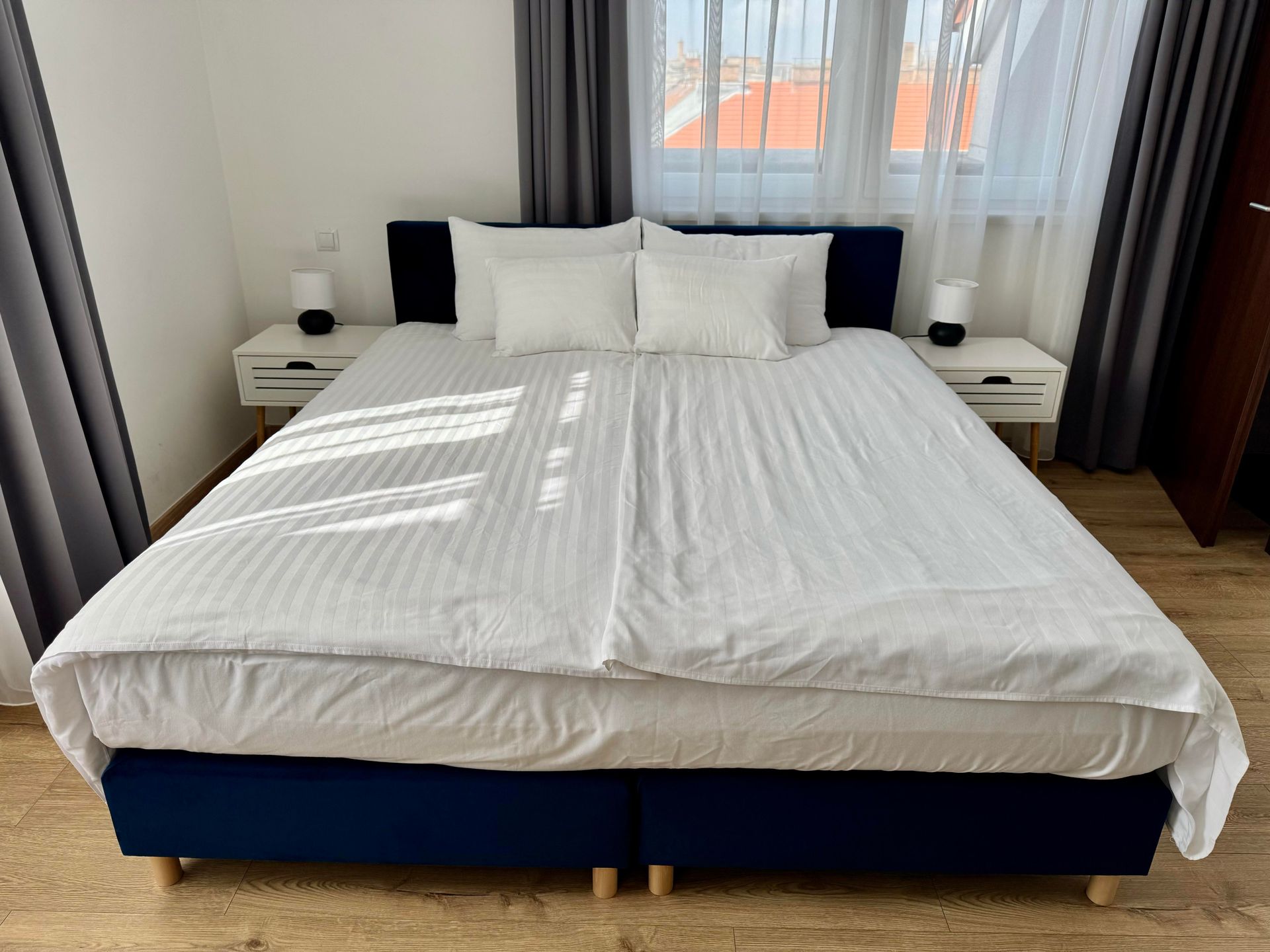 Bedroom with blue bed frame, white bedding, nightstands, and window.