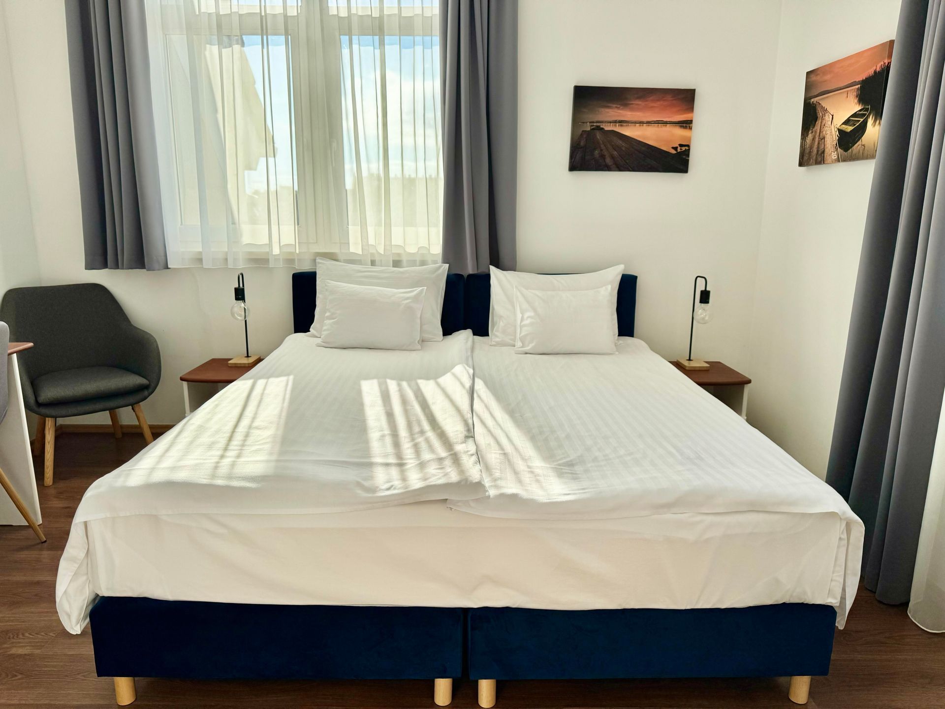 Bedroom with a large bed, two bedside tables, a chair, and two framed pictures on the wall.