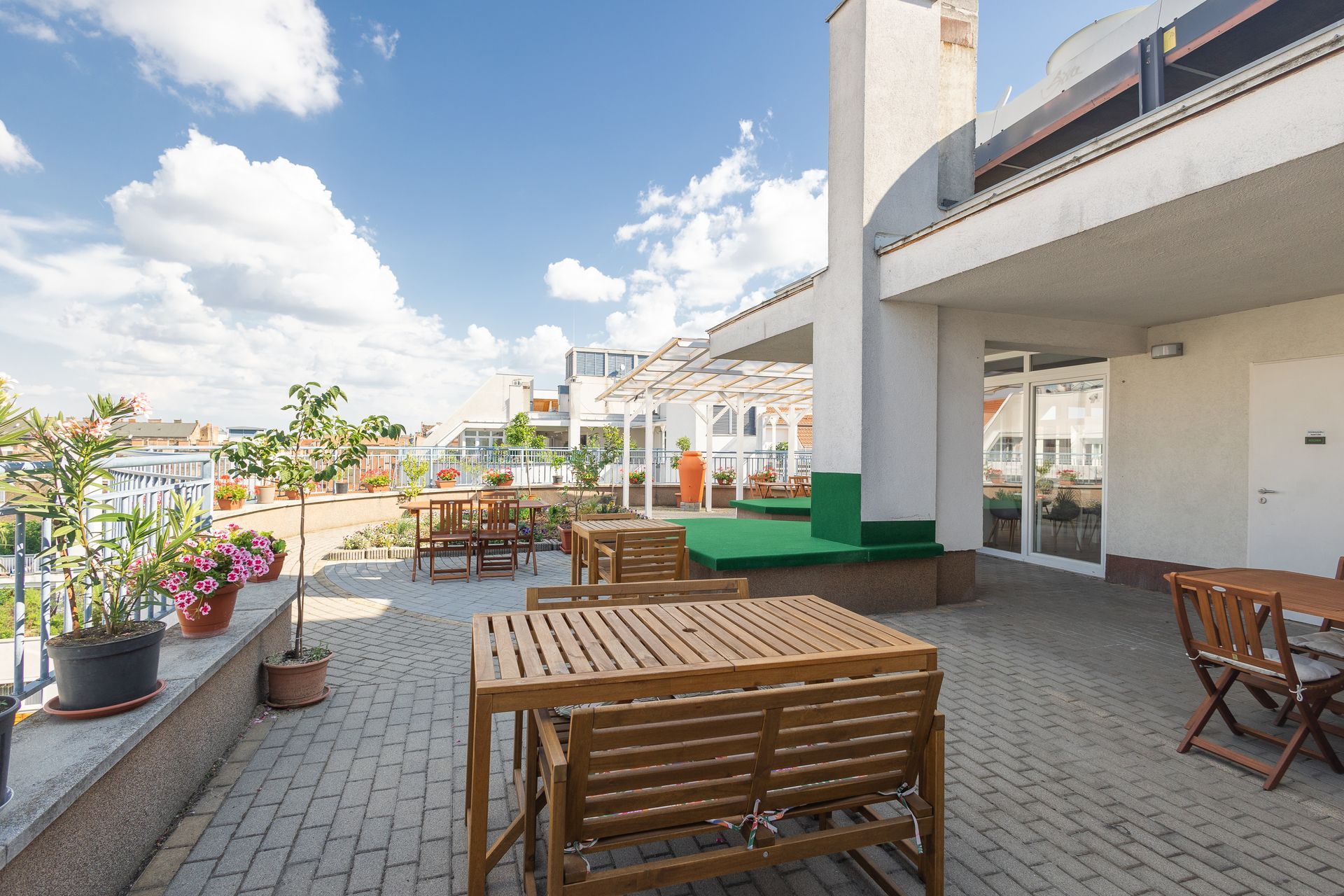 Outdoor patio with tables and chairs, under a blue sky with clouds.