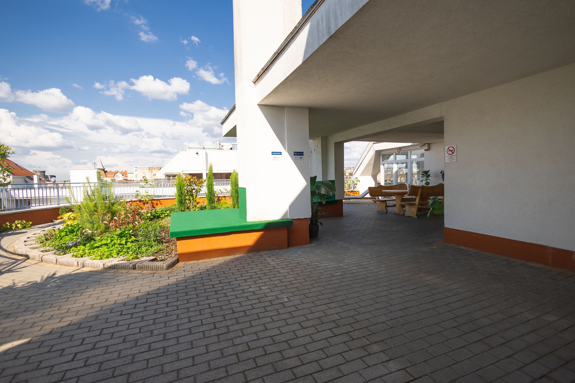 Exterior building with covered walkway and rooftop garden under a blue sky.