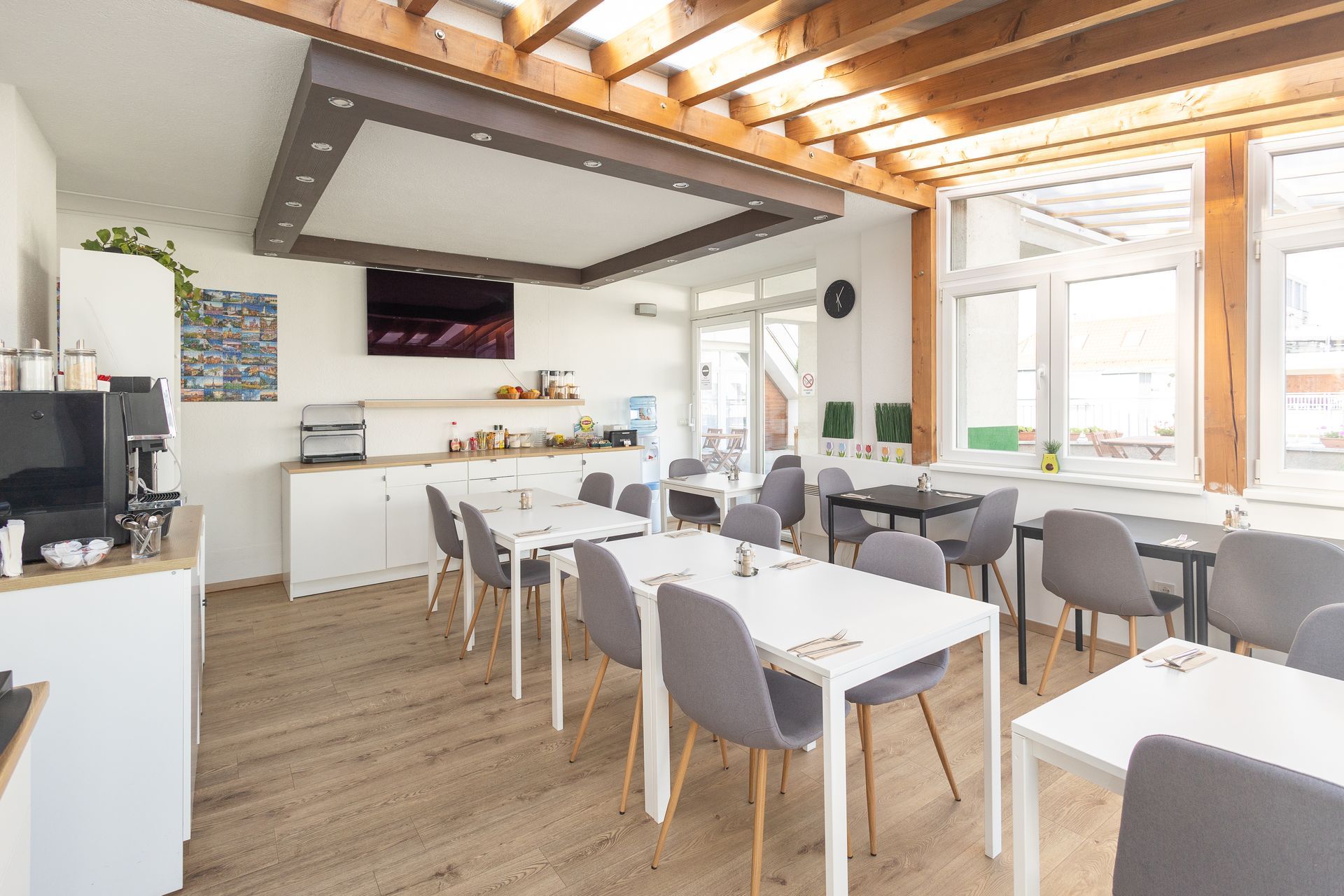 Bright dining room with white tables and chairs, buffet area, and large windows.