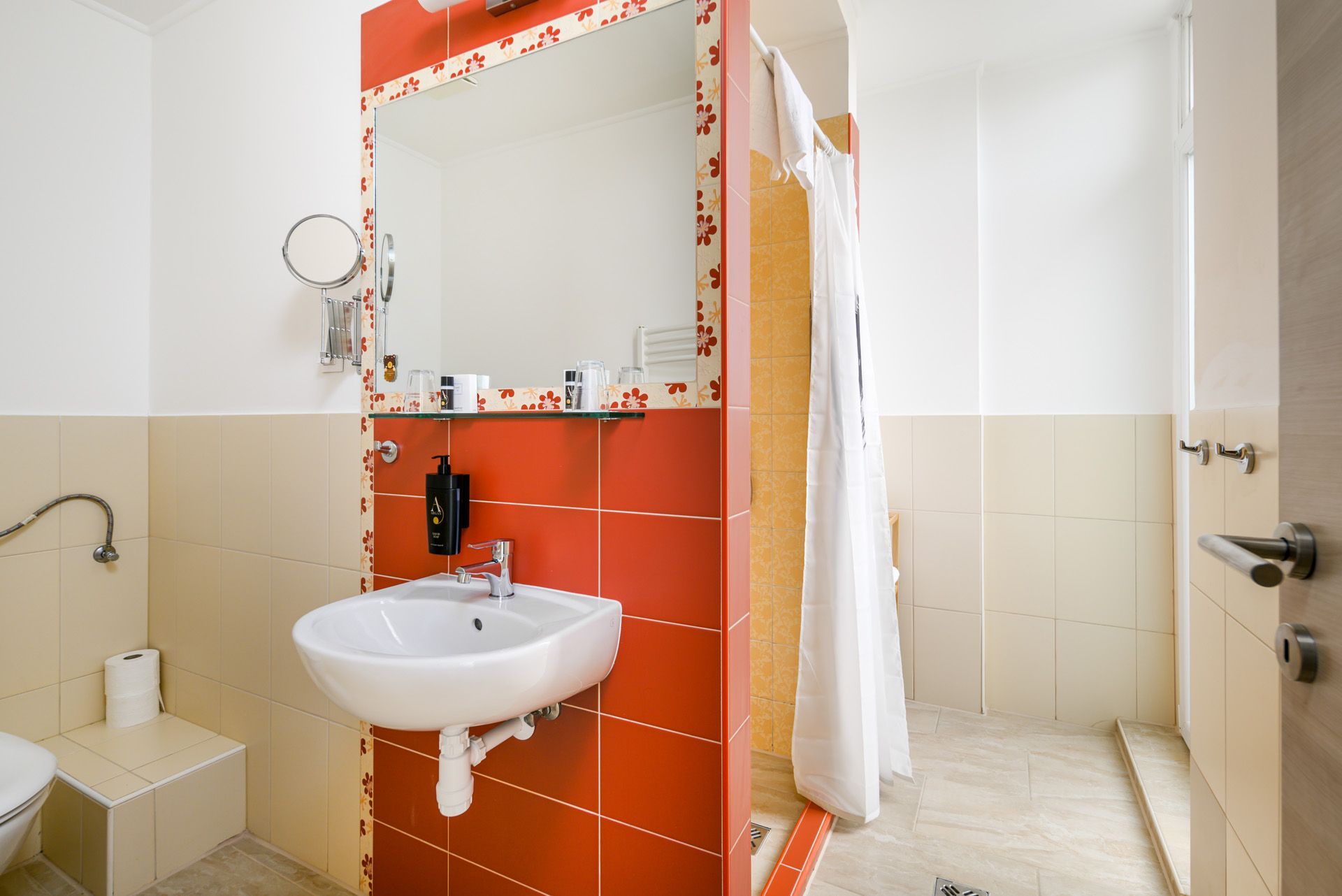 Bathroom with red tiled wall, white sink, mirror, and shower curtain.