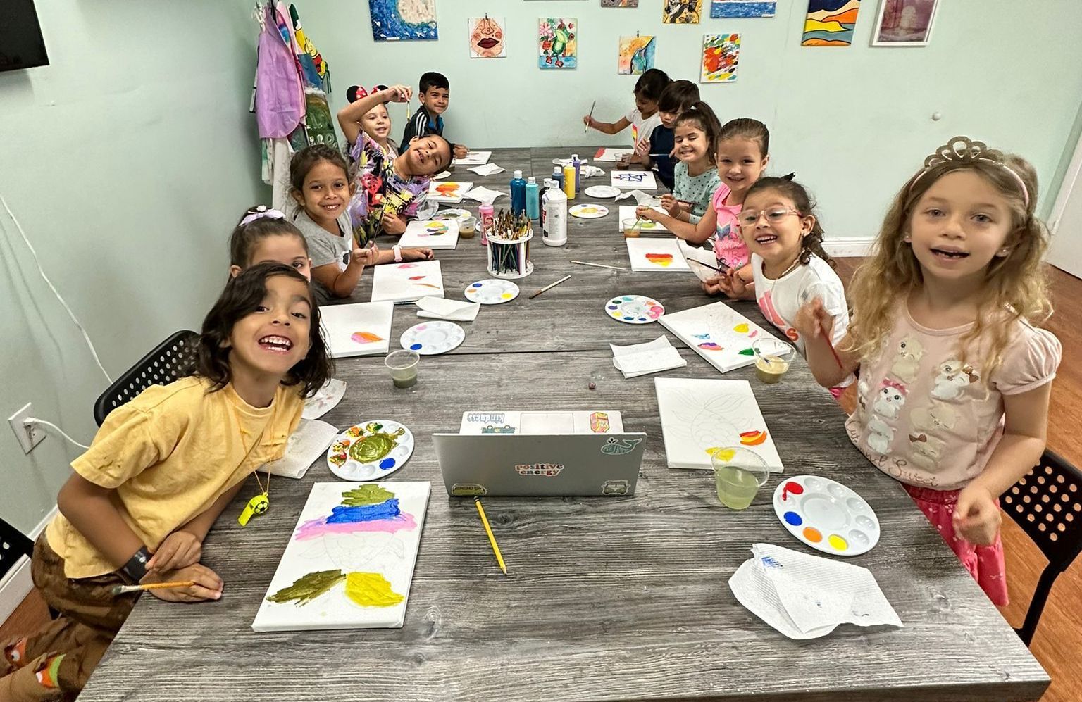 A group of children are sitting at a table painting.