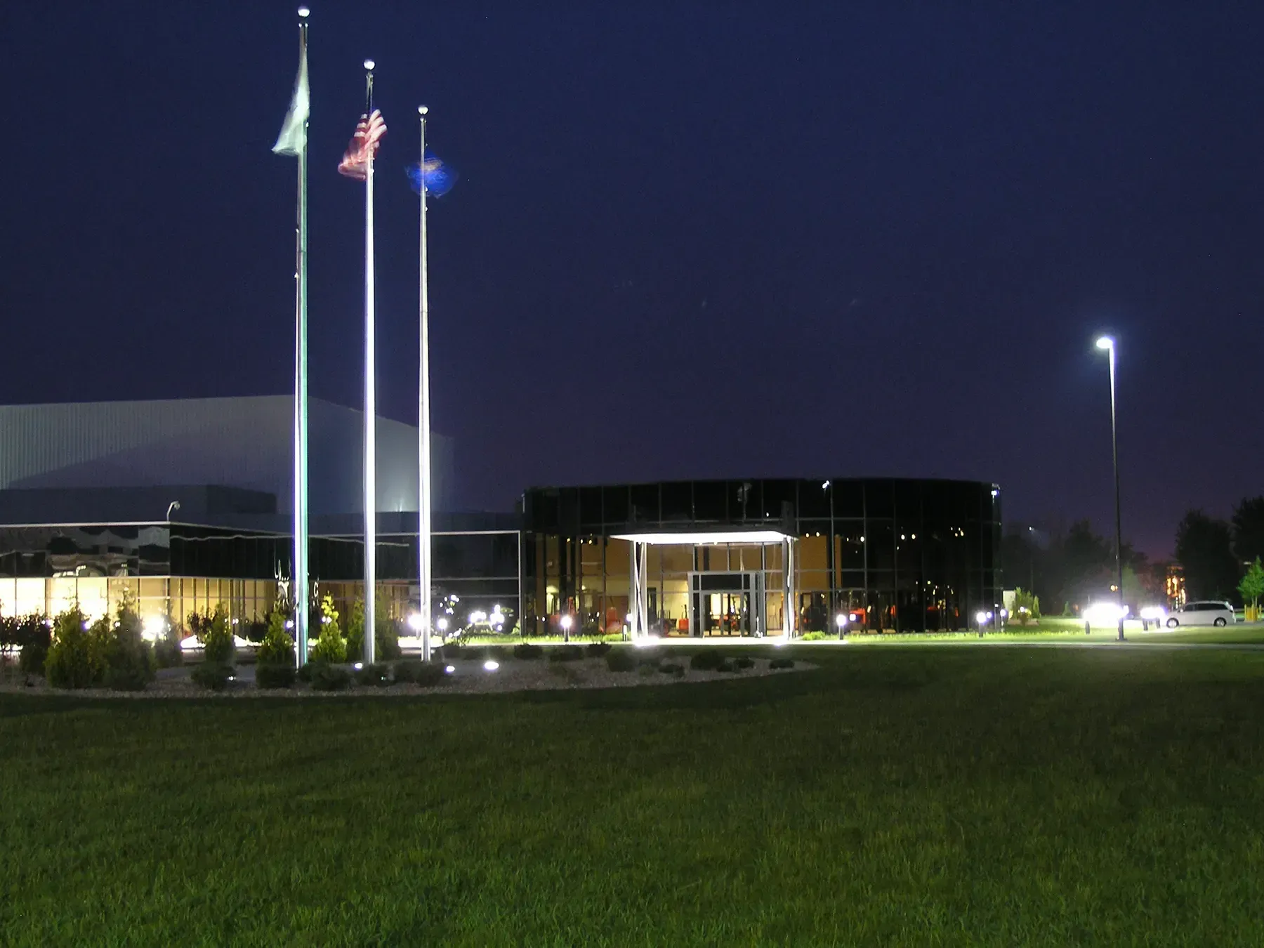 A row of flags are flying in front of a building at night
