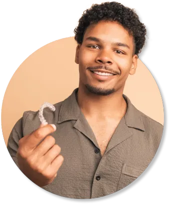 A man is holding a clear retainer in his hand and smiling.