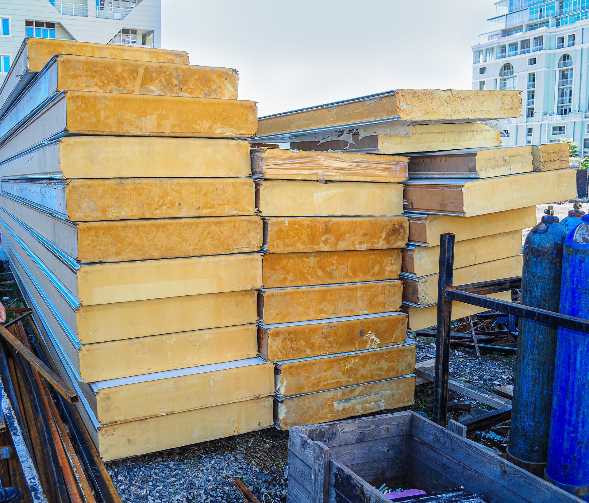 Stacks of yellow insulation boards piled on pallets at an outdoor industrial site.