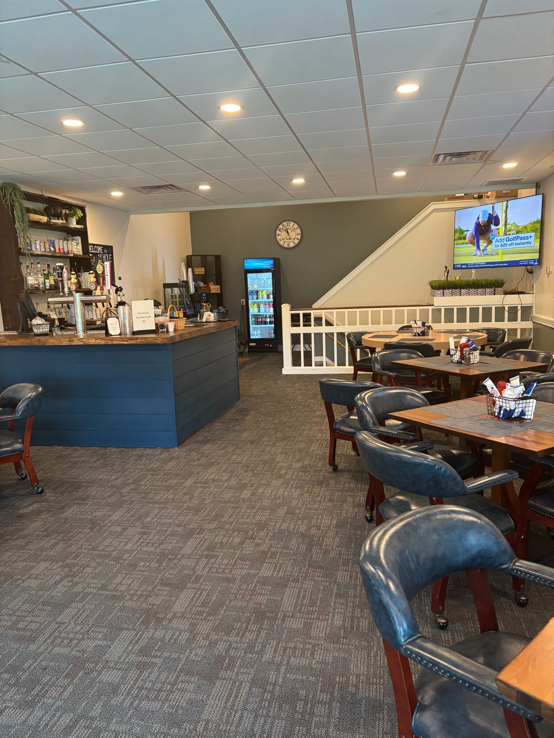 Quiet restaurant dining area with blue booths, bar counter, tables, and a TV on the wall.