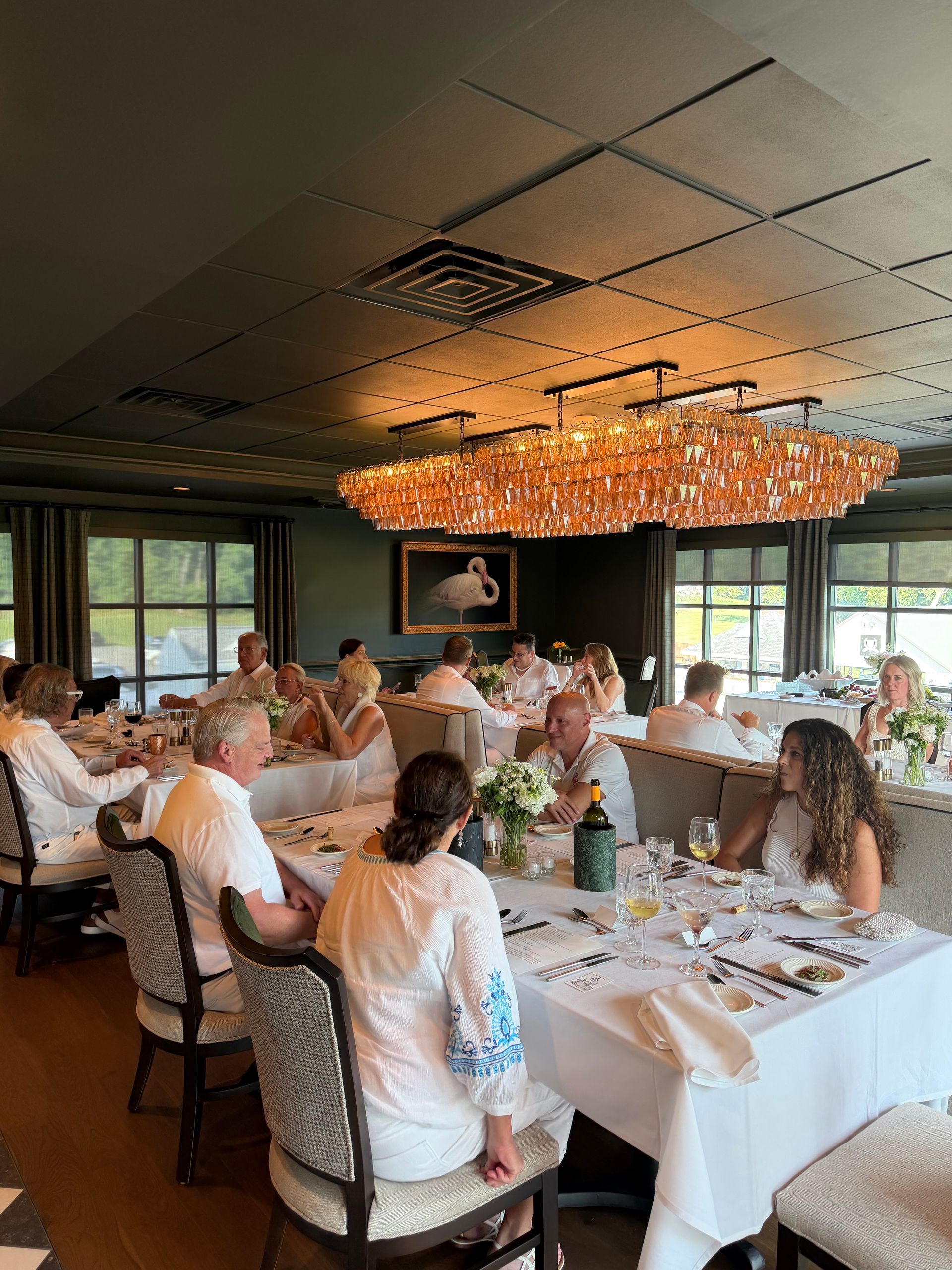 Guests dining at a formal banquet table under a warm chandelier in a restaurant.
