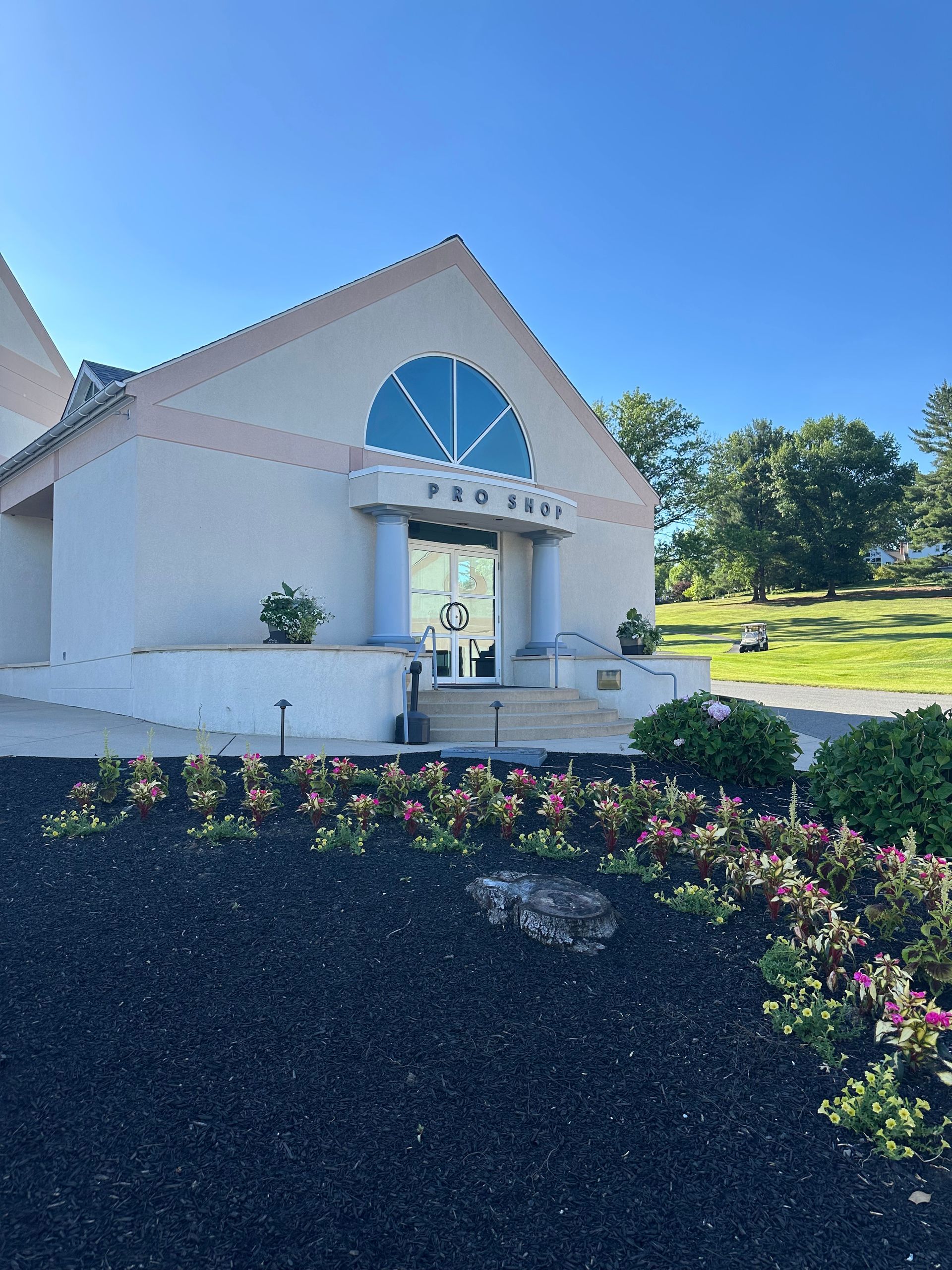 White church with arched window and flower bed under a bright blue sky