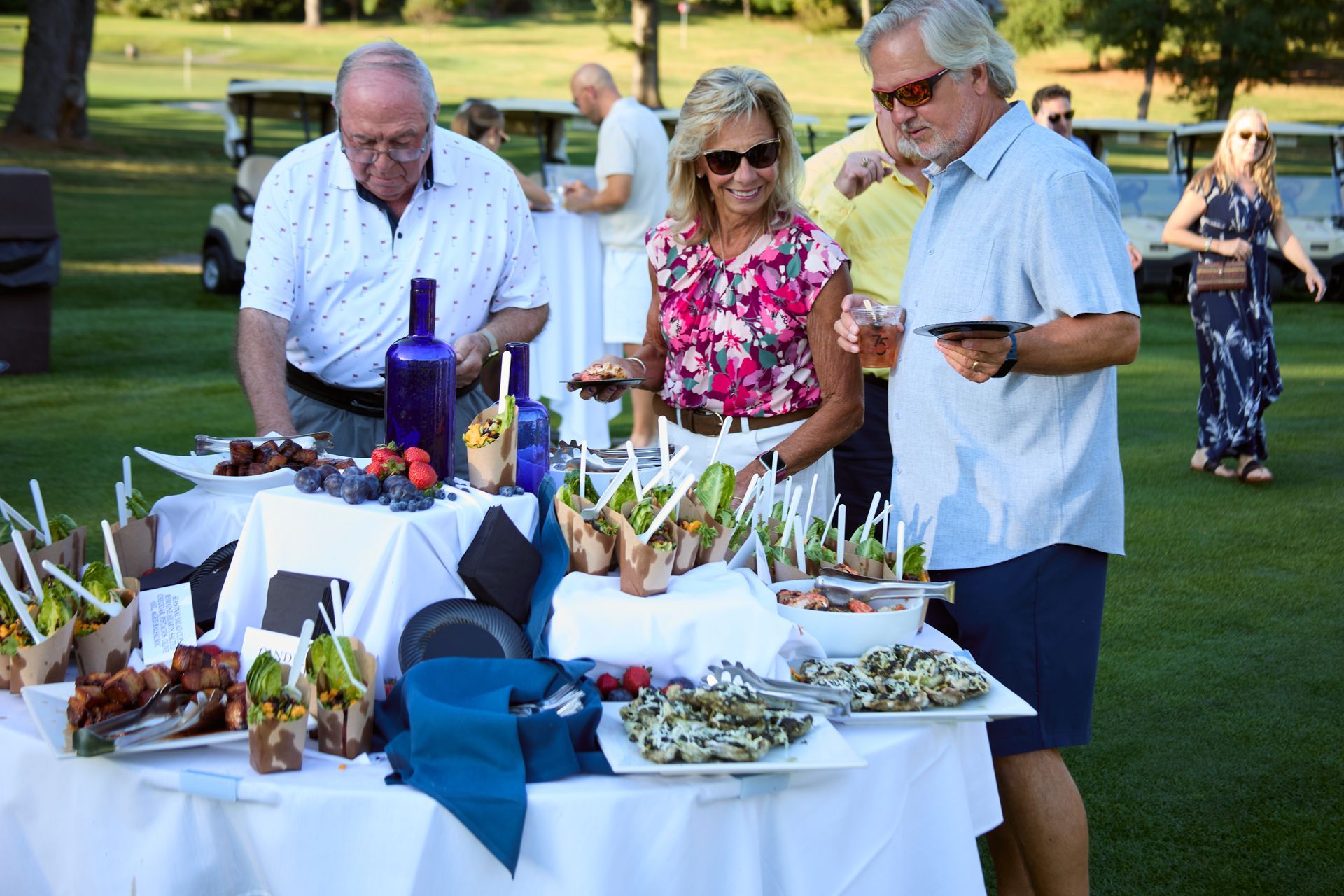 People serving themselves from a buffet table at an outdoor garden gathering