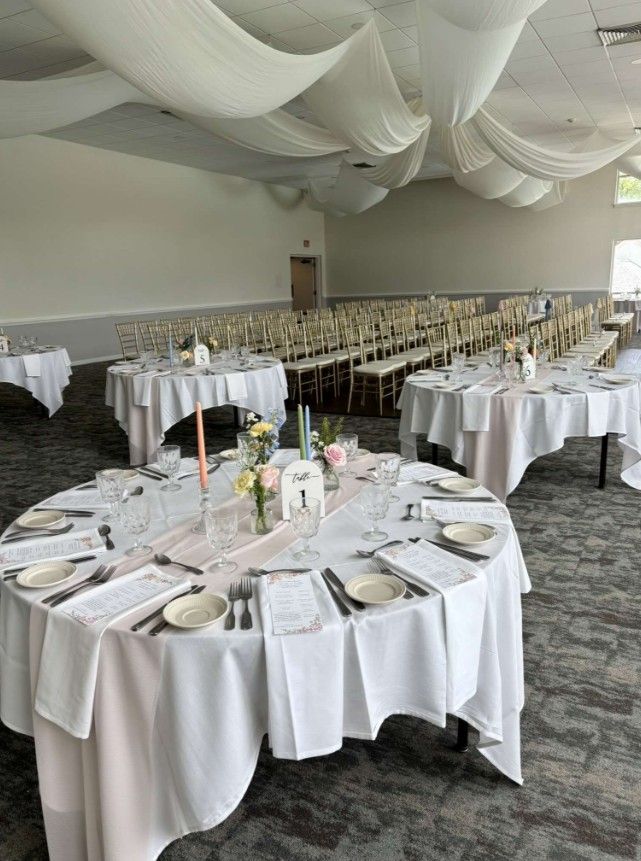 Balloon-decorated banquet hall with round tables set for an event and pastel hanging decorations.