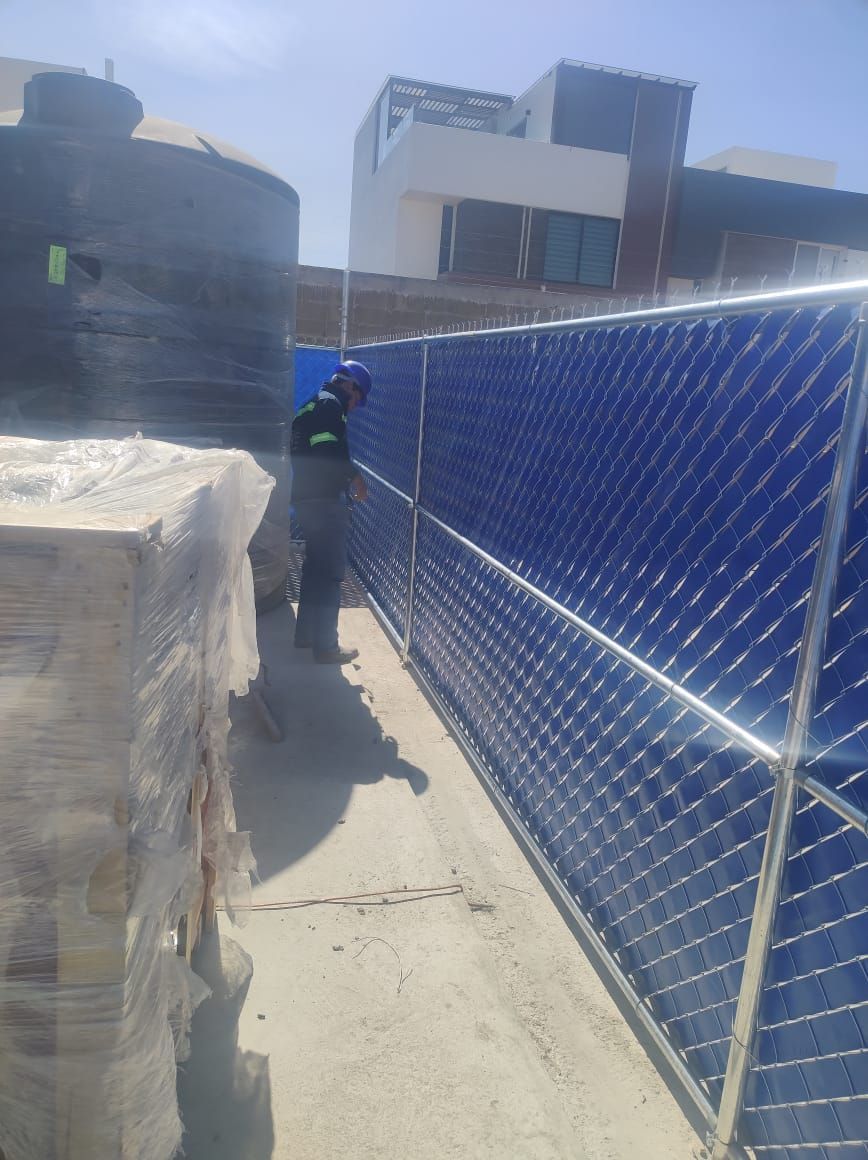 Un trabajador de la construcción instala paneles solares en un tejado, con paneles azules y cielo despejado.