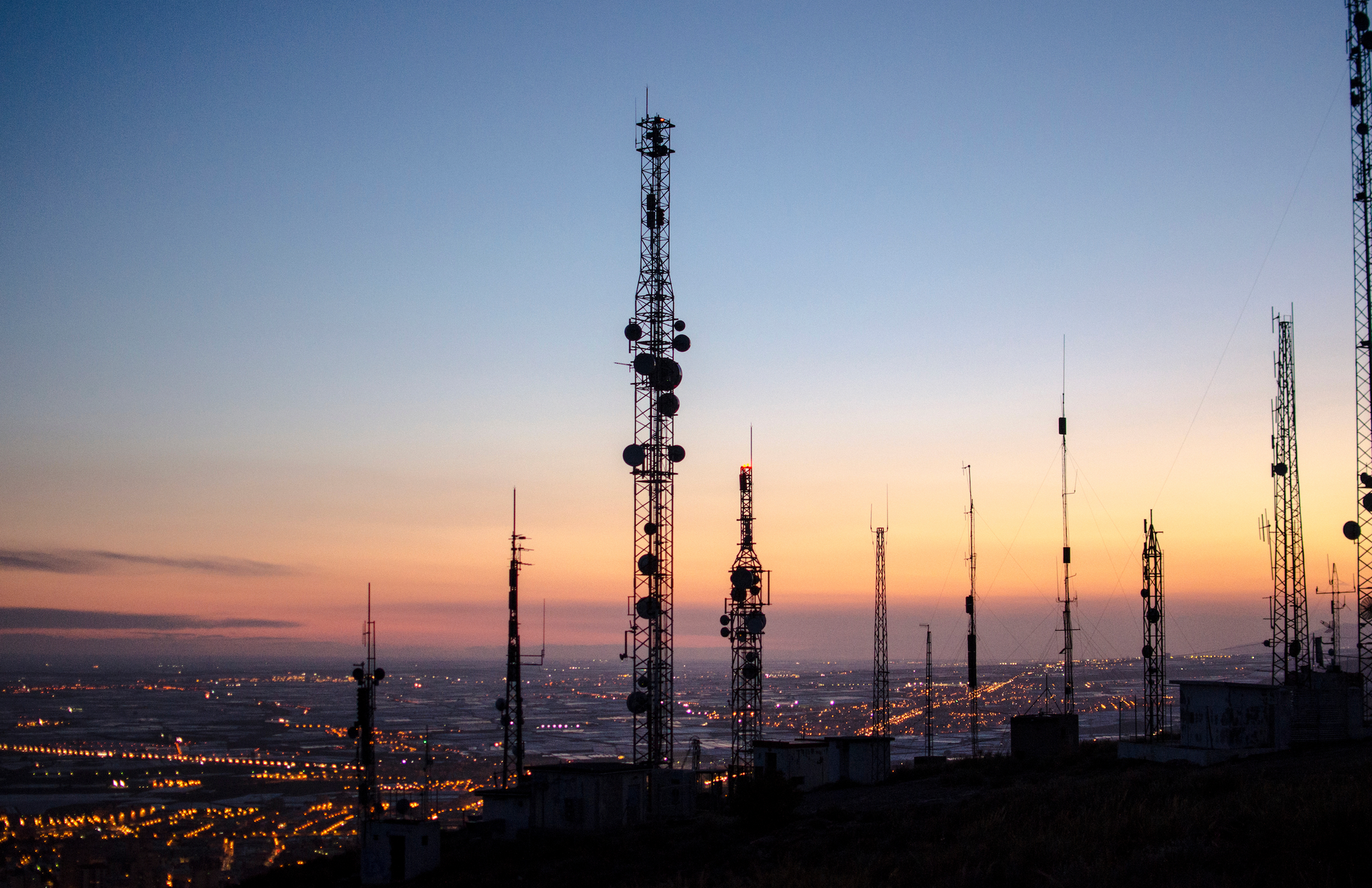 A sunset over a city with a lot of antennas in the foreground