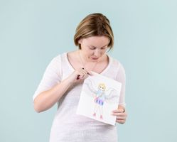 A woman is holding a drawing of an angel.