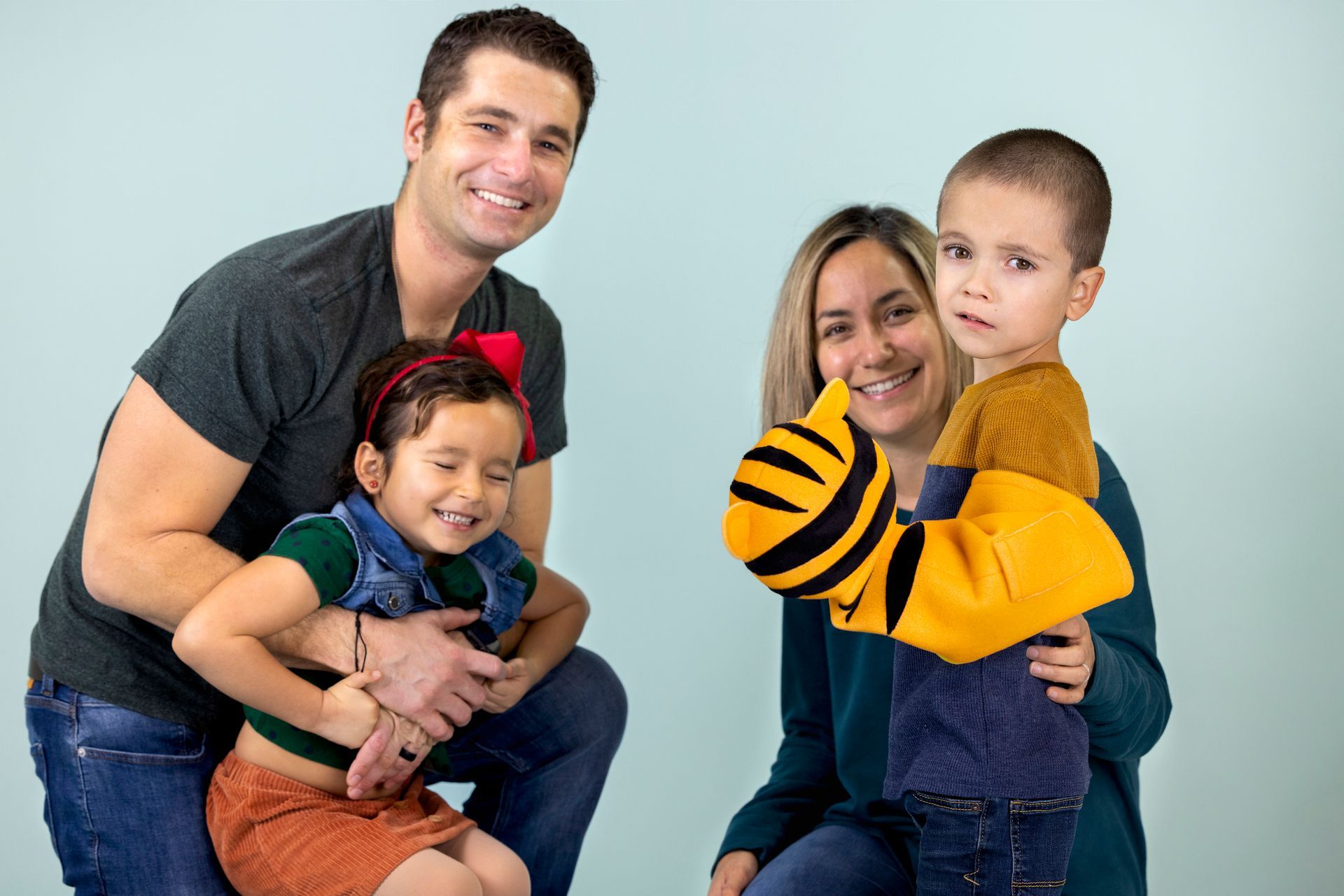 A family is posing for a picture together and one of the children is wearing a tiger hand puppet.