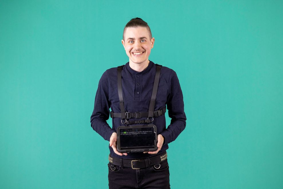 A young man is holding a tablet in his hands and smiling.