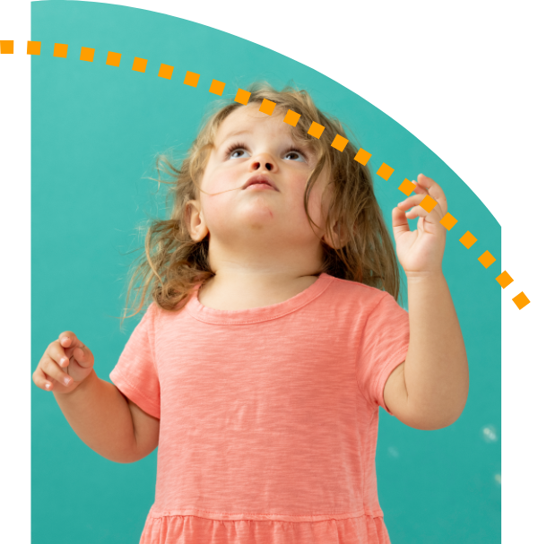 A little girl in a pink dress is looking up at something