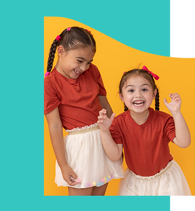 Two little girls are standing next to each other and smiling.