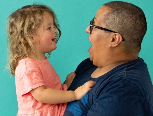 A man is holding a little girl in his arms.