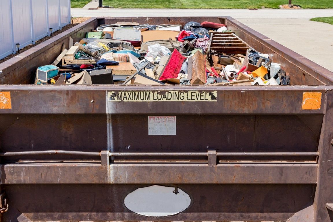 Overflowing construction dumpster filled with mixed debris in a parking lot
