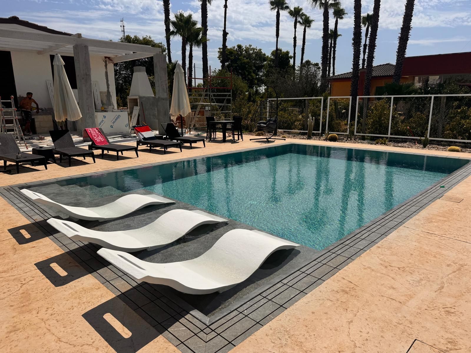 piscina a sfioro in giardino privato con area relax telo alkorplan touch urban pool design group