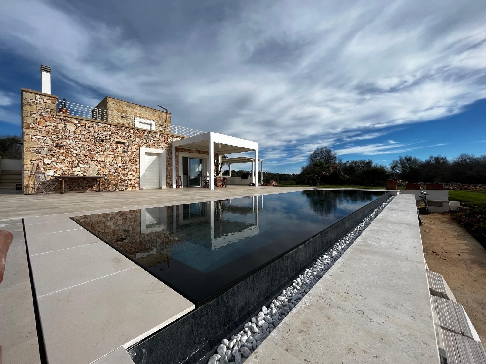 piscina a sfioro trilogy+infinity colore telo alkorplan touch elegance e bordo in marmo nero pool design group