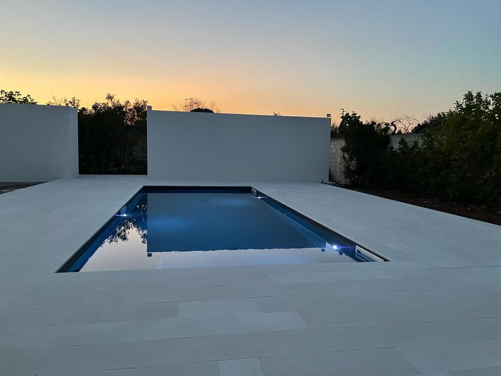 piscina interrata con skimmer in giardino colore grigio scuro e pavimentazione di trani