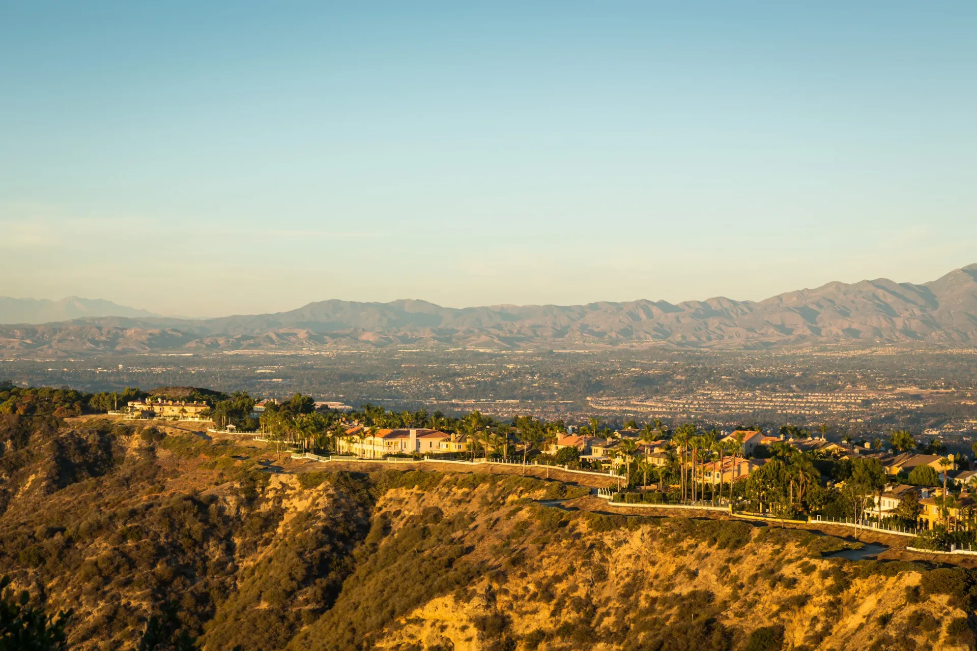 Panoramic hillside neighborhood with houses along a ridge and distant mountains
