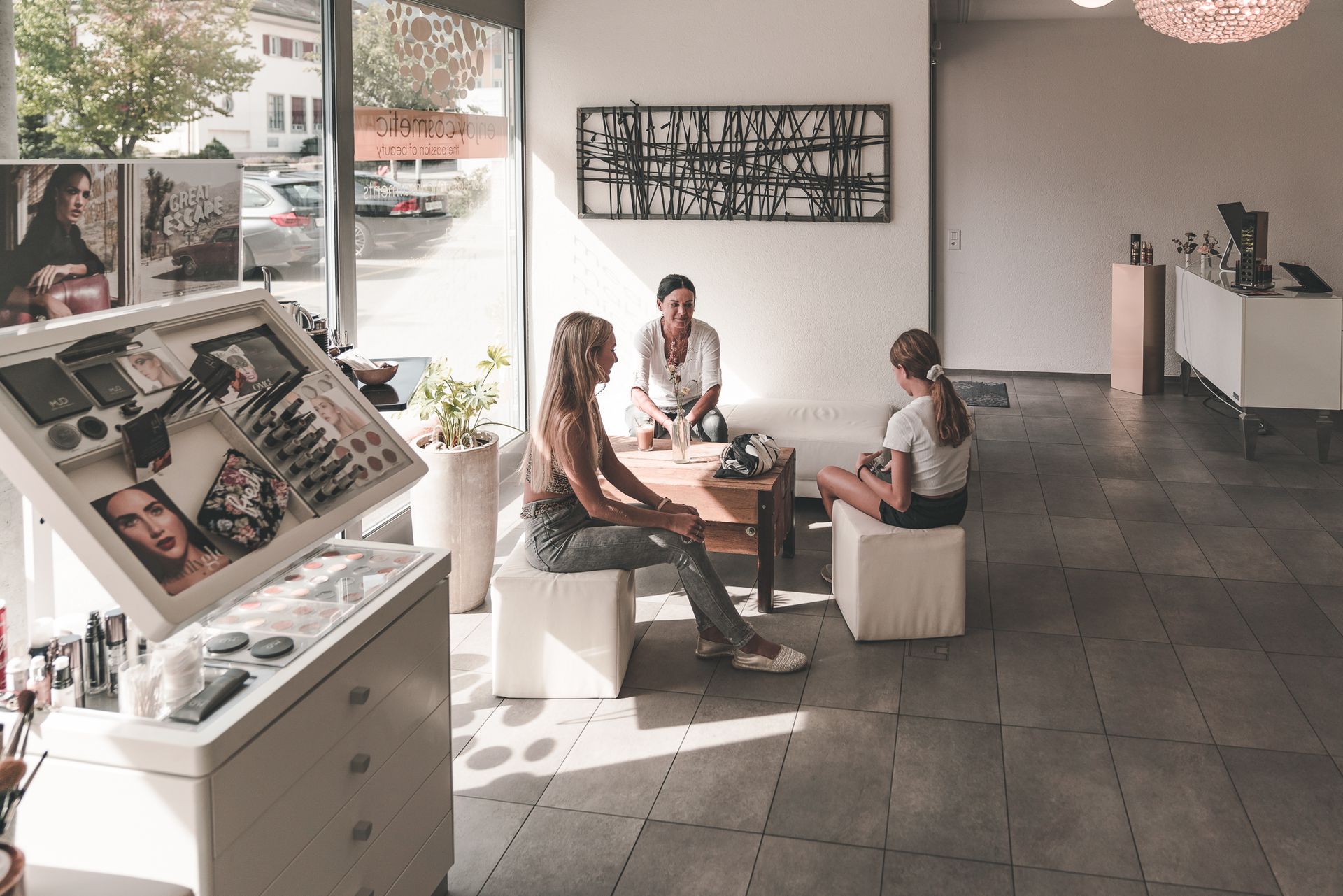 Eine Gruppe von Frauen sitzt in einem Salon an einem Tisch.