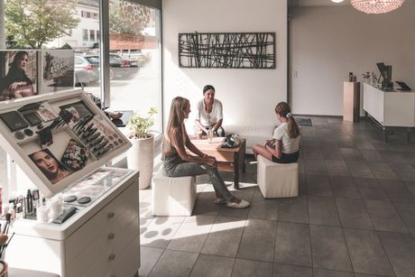 Eine Gruppe von Frauen sitzt in einem Salon an einem Tisch.
