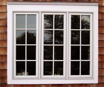 There are three windows on the side of a house.