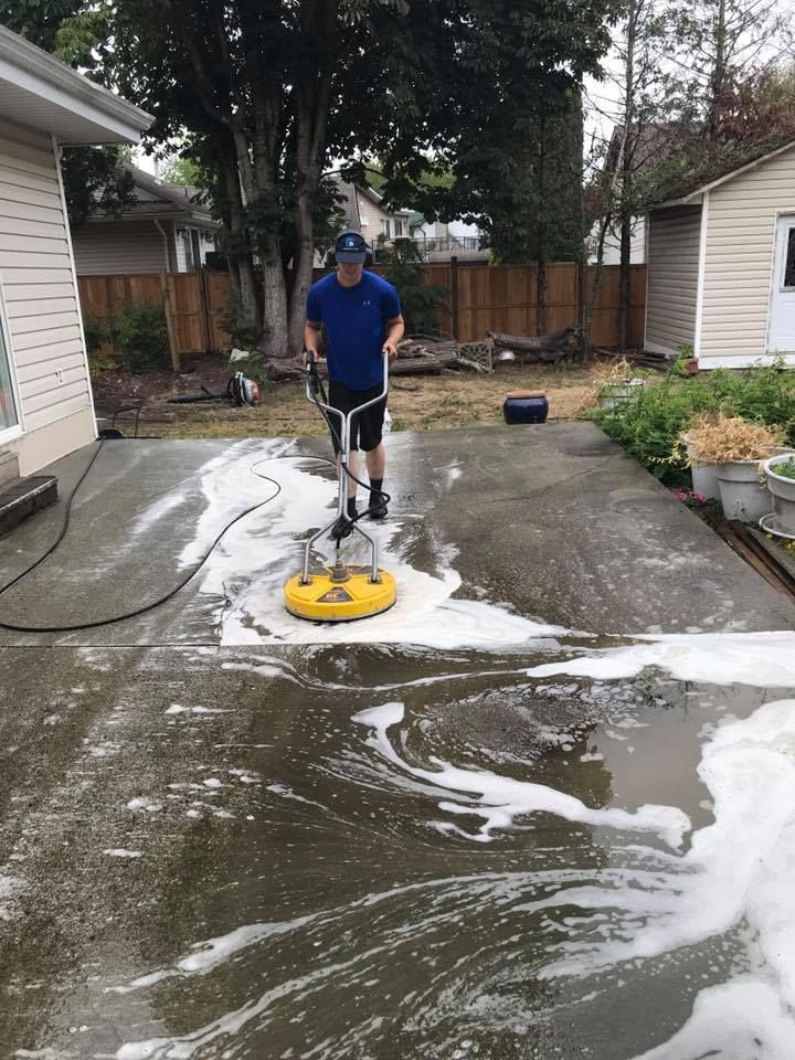 A man is cleaning a driveway with a machine.