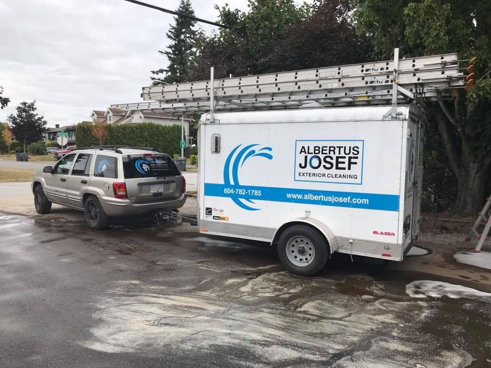 A car is parked next to a trailer that says albertus josef on it.