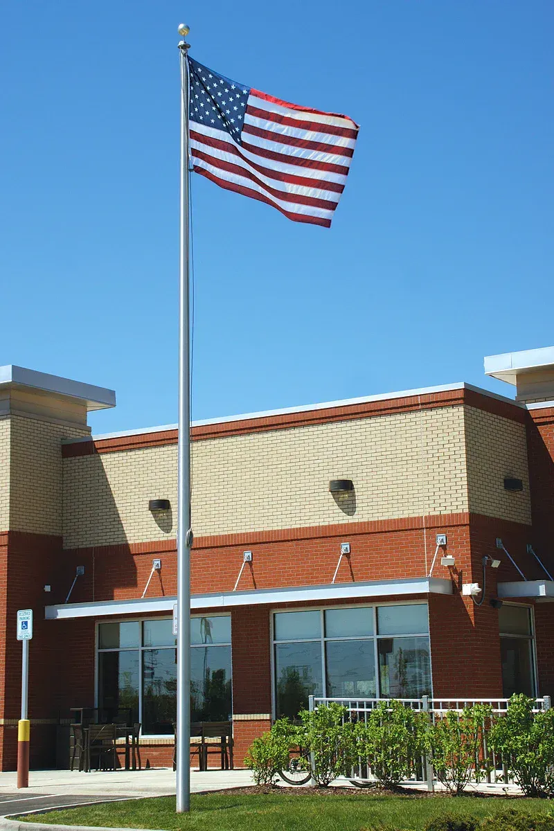 American flag on a pole outside a brick building under a clear blue sky