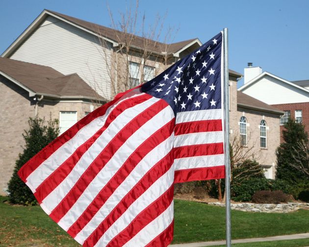 American flag waving in front of suburban houses on a sunny day