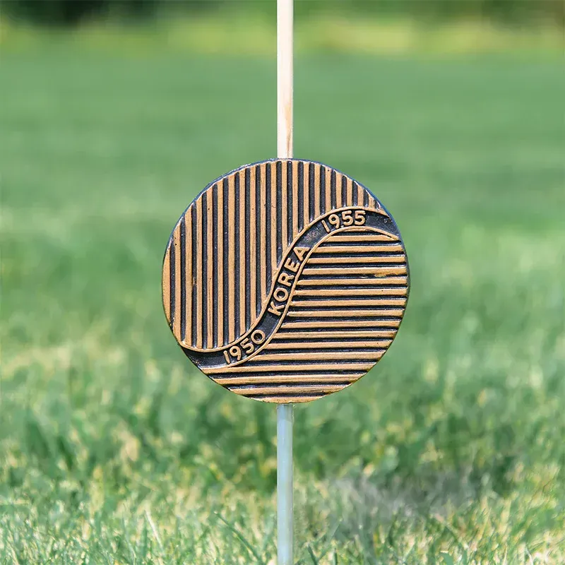 Copper-toned circular medal with black striped design and “1950 KOREA 1955” inscription