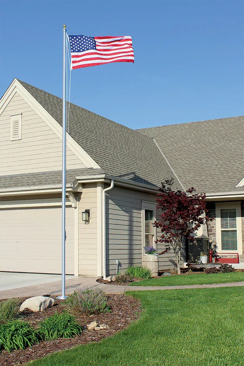 Suburban house with an American flag on a pole in the front yard under a clear blue sky