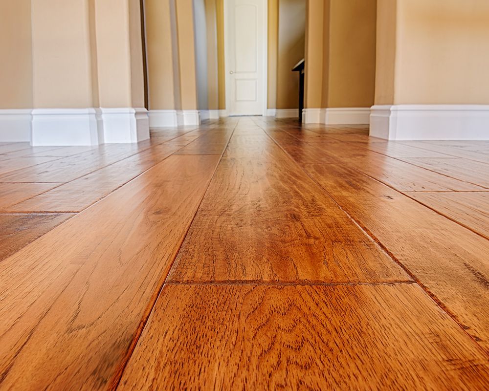 A hallway with hardwood floors and white trim in a house.