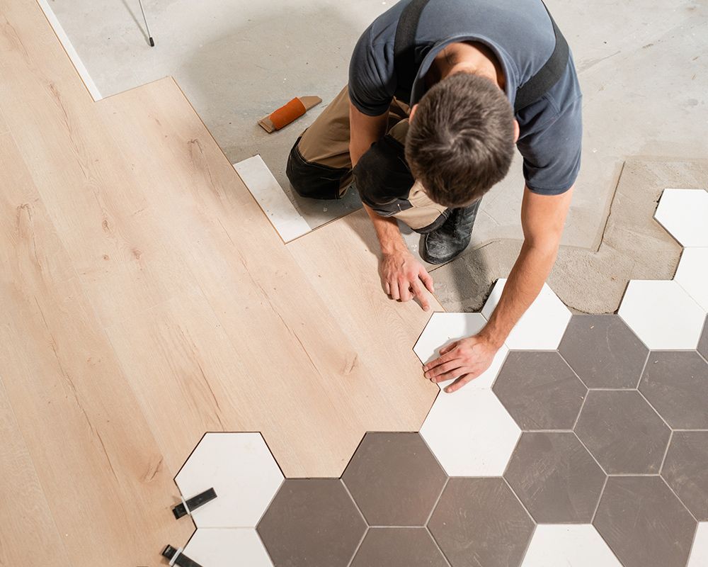 A man is installing a wooden floor with hexagonal tiles.