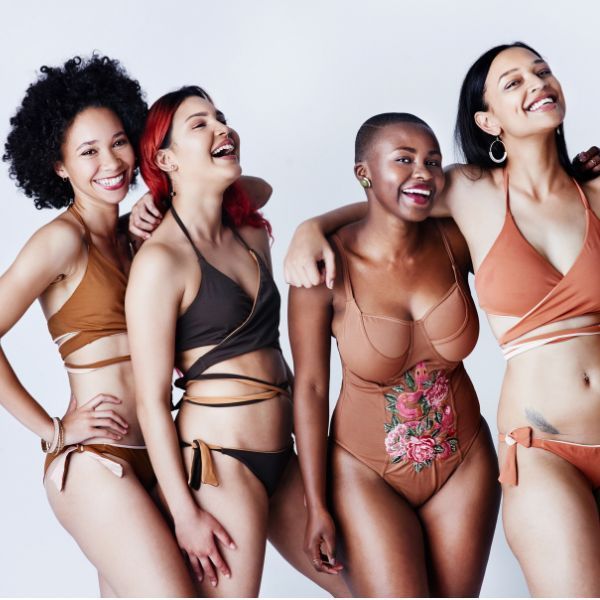 Four diverse women in swimwear, smiling and embracing, against a white backdrop. confident after HIFU