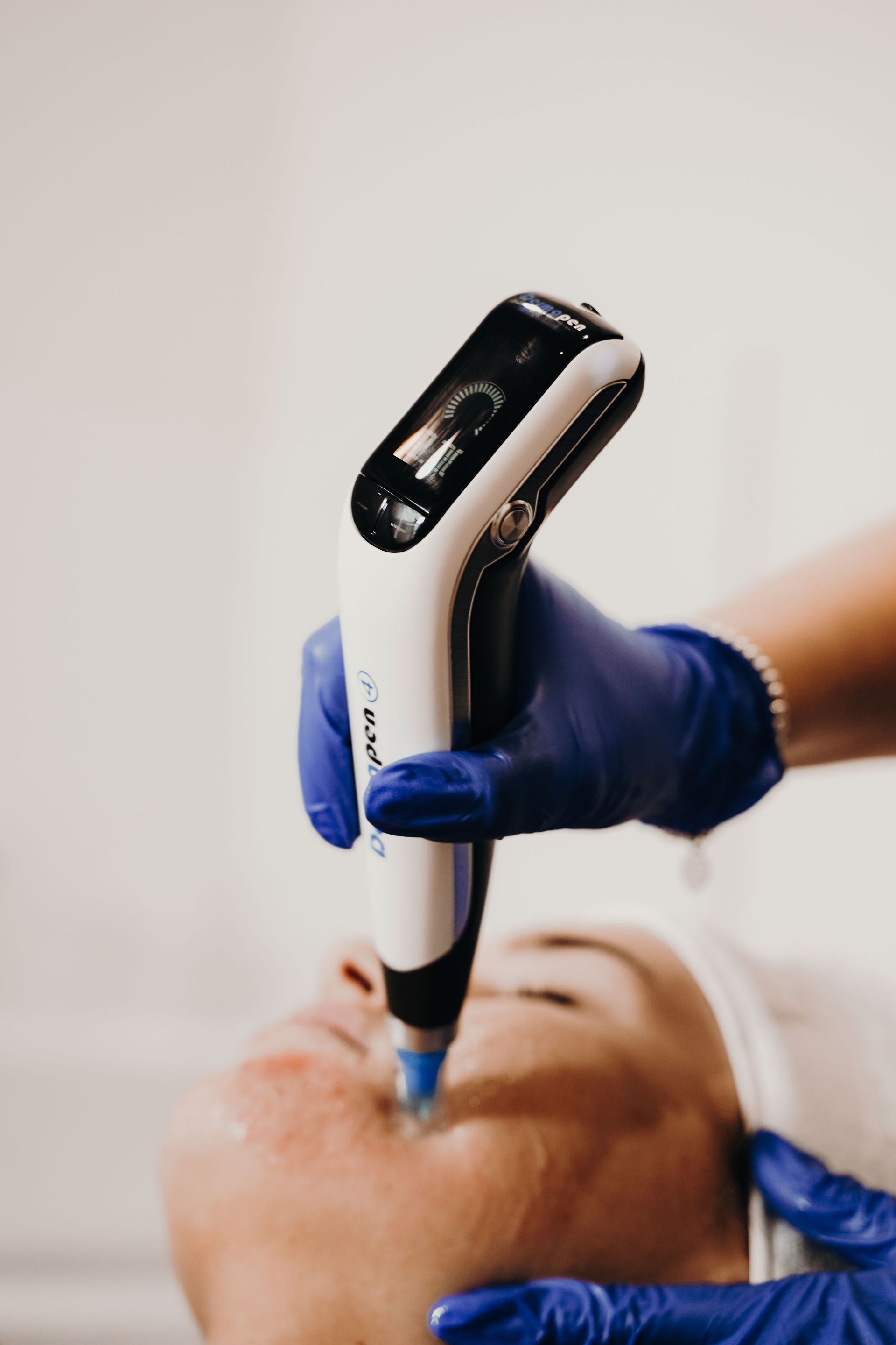 Person receiving a facial treatment with a handheld device, blue gloves.