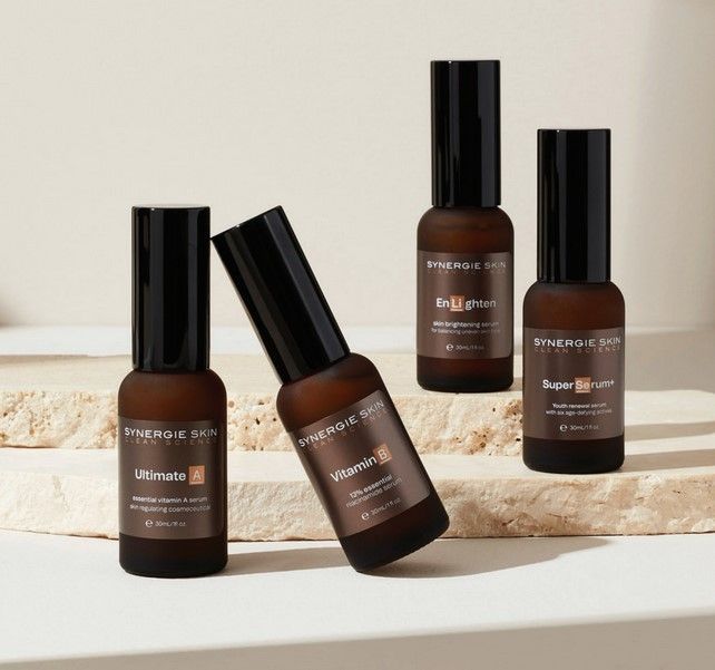 Four brown skincare product bottles on a neutral stone surface.