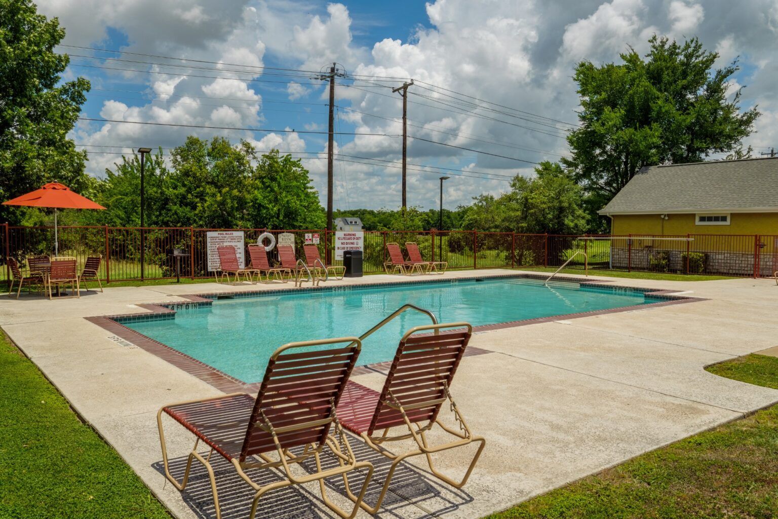 Outdoor swimming pool with two lounge chairs on a sunny day