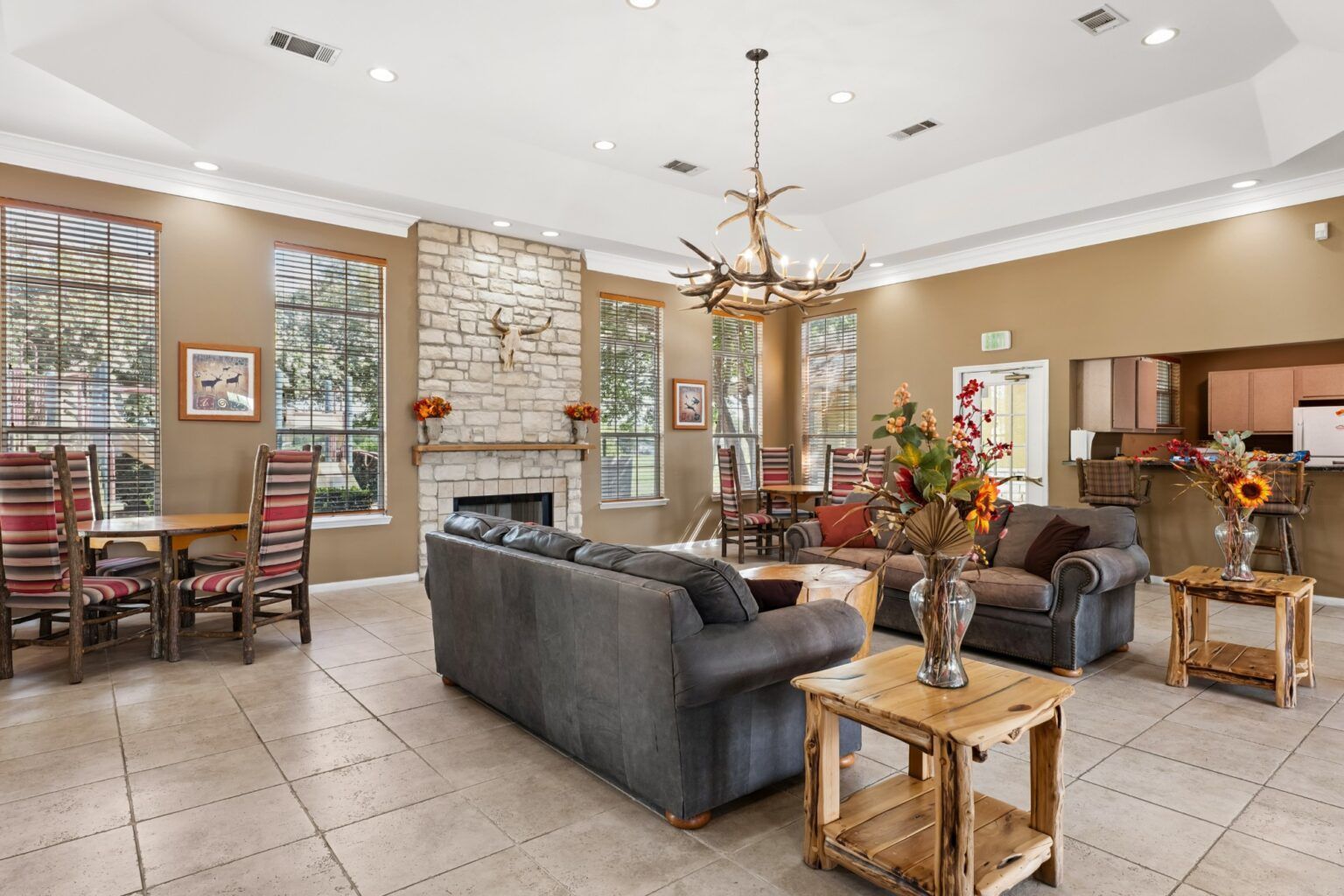 Spacious lodge-style lobby with gray sofas, stone fireplace, dining tables, and large windows