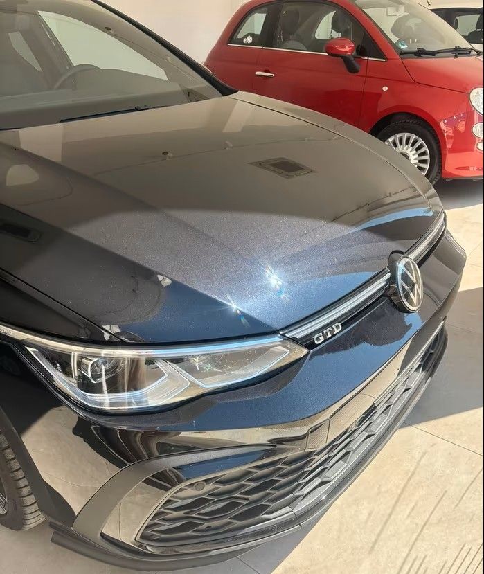 Volkswagen Golf GTI blu scuro, Fiat 500 rossa sullo sfondo. 