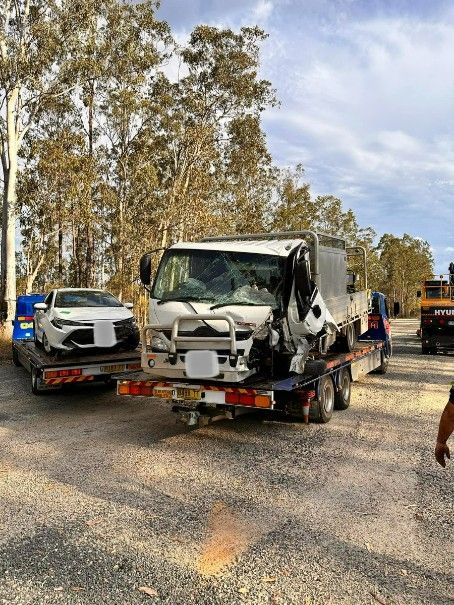 A Tow Truck is Carrying a Damaged Car on a Trailer — TNT Towing - Coffs Clarence in Maclean, NSW