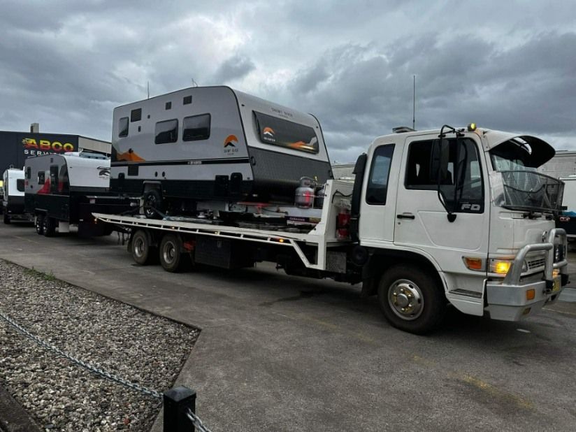 A Tow Truck is Carrying a Trailer With a Camper on It — TNT Towing - Coffs Clarence in Maclean, NSW