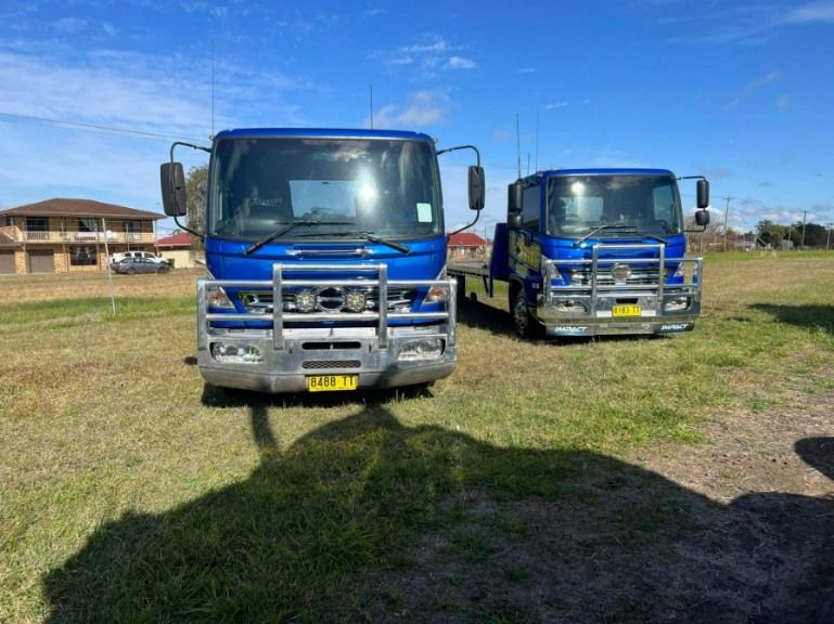 Two large trucks are parked side by side on a paddock — TNT Towing - Coffs Clarence in Lismore, NSW
